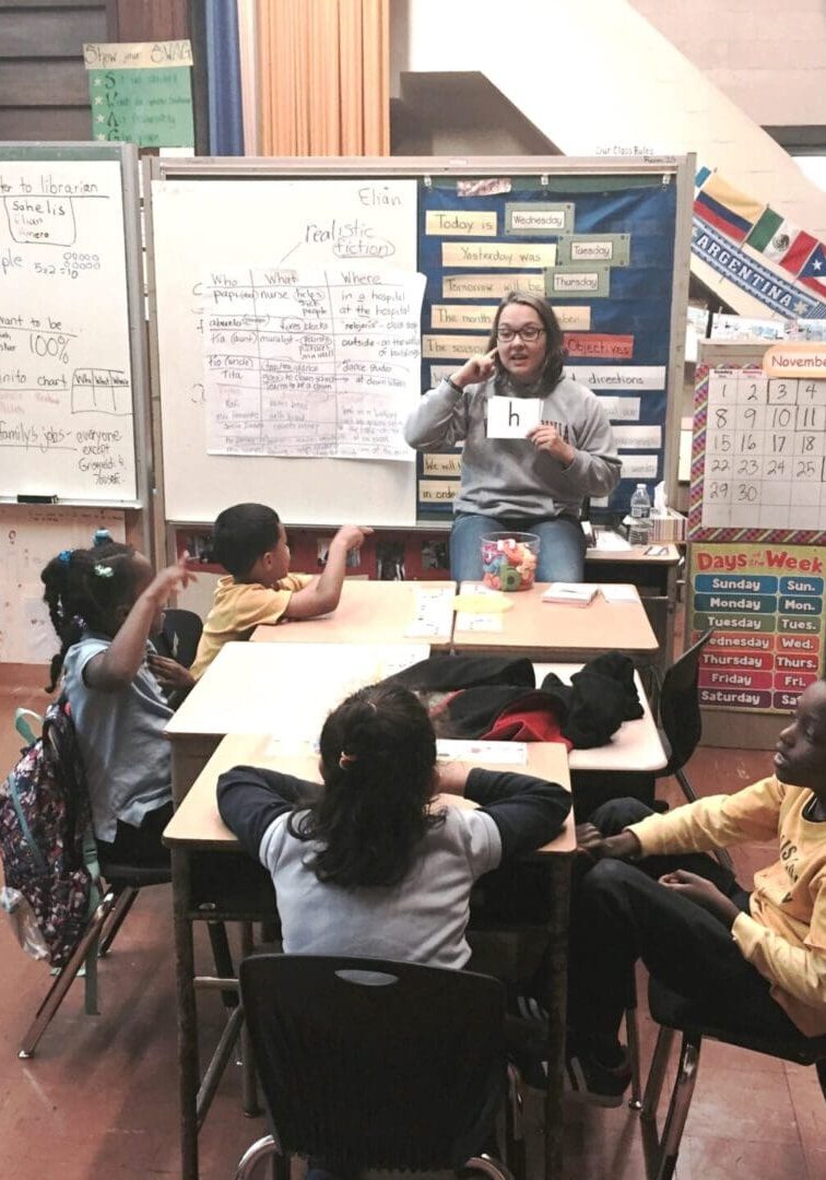 A teacher holding a flash card in front of kids